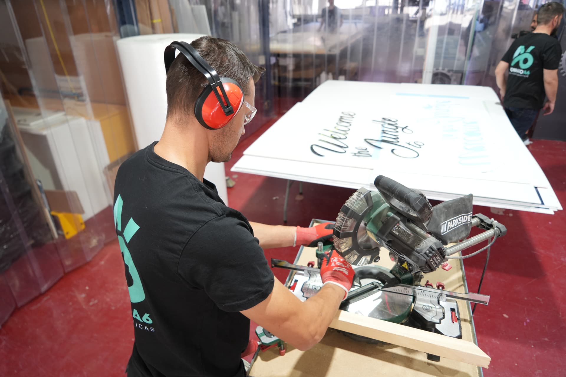 Técnico cortando paneles rotulados en el taller